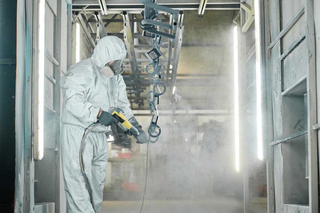man inside paint sprayer room for surface treatment services